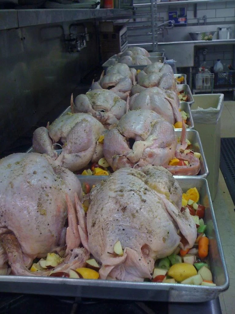 Whole chickens being prepared for roasting in the kitchen